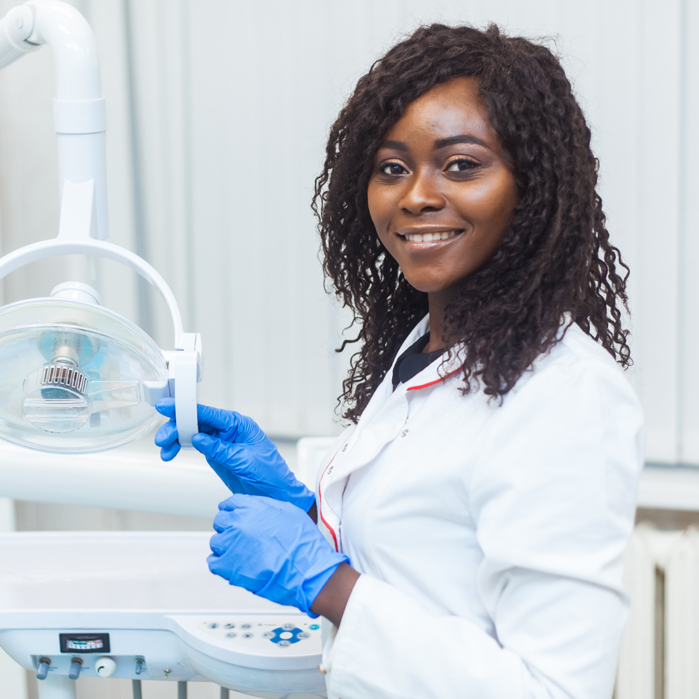 Portrait of Female black dentist in dental office. She standing at her office and she has beautiful smile. Modern medical equipment